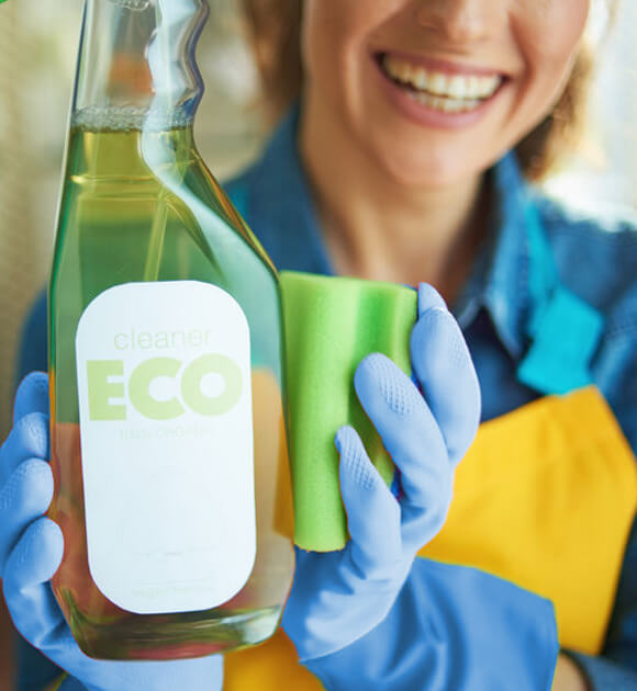 Supreme Cleaning Adelaide. Picture of a happy lady holding an Eco friendly cleaning bottle, while doing her domestic cleaning.