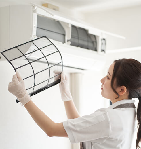 Supreme Cleaning & Care Services photo of a home care worker cleaning the filter from a home air conditioner.